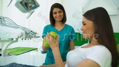 友好的口腔医生给女人苹果，耐心吃水果，口腔健康